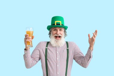 Mavi arka planda bir bardak birası olan mutlu son sınıf öğrencisi. Aziz Patrick Günü kutlaması