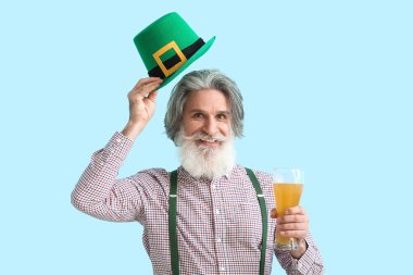 Mavi arka planda şapkası ve bir bardak birası olan son sınıf öğrencisi. Aziz Patrick Günü kutlaması