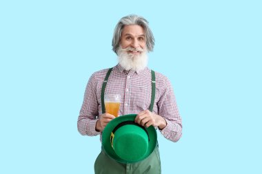 Mavi arka planda şapkası ve bir bardak birası olan son sınıf öğrencisi. Aziz Patrick Günü kutlaması