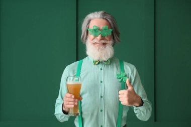 Yeşil arka planda bir bardak birası olan son sınıf öğrencisi. Aziz Patrick Günü kutlaması