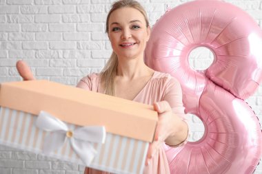 Beyaz tuğla duvarlı arka planda hediye kutusu olan kadın. Uluslararası Kadınlar Günü kutlamaları