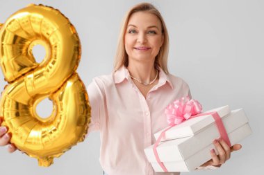 Arkaplanda hediye kutuları ve balon şeklinde sekiz figürlü bir kadın. Uluslararası Kadınlar Günü kutlamaları