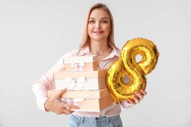 Elinde bir sürü hediye kutusu ve balon olan bir kadın var. Işık arka planda 8 şeklinde. Uluslararası Kadınlar Günü kutlamaları