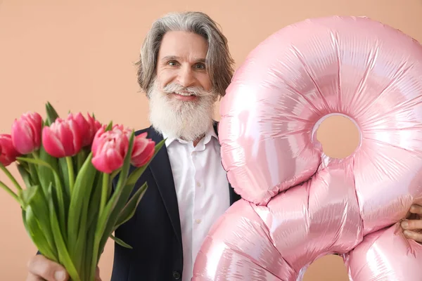Şekil 8 şeklinde balon tutan yaşlı bir adam ve renkli arka planda bir buket lale. Uluslararası Kadınlar Günü kutlamaları