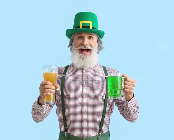 Mavi arka planda bira bardakları olan mutlu son sınıf öğrencisi. Aziz Patrick Günü kutlaması