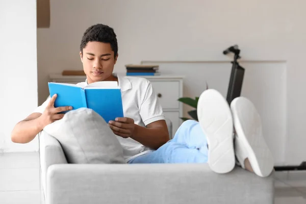 Studente Afroamericano Maschio Che Legge Libro Sul Divano — Foto Stock