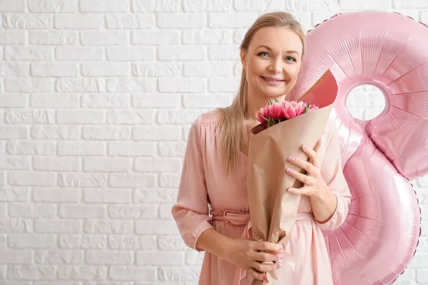 Beyaz duvarda bir buket lale olan bir kadın. Uluslararası Kadınlar Günü kutlamaları