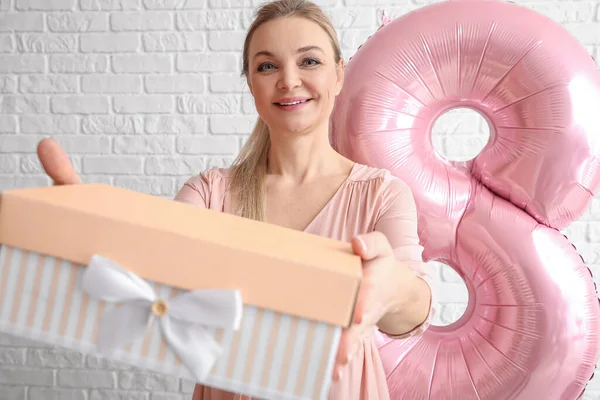 Beyaz tuğla duvarlı arka planda hediye kutusu olan kadın. Uluslararası Kadınlar Günü kutlamaları