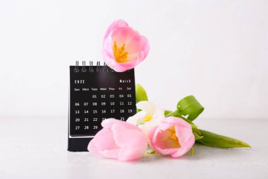 Uluslararası Kadınlar Günü kutlamaları için takvim ve çiçekler açık arkaplanda