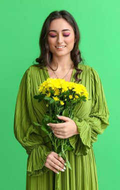 Yaratıcı makyajlı bir kadın yeşil arka planda güzel çiçekler tutuyor. Uluslararası Kadınlar Günü