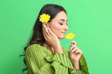 Yaratıcı makyajı ve yeşil arka planda kasımpatı çiçekleri olan bir kadın. Uluslararası Kadınlar Günü