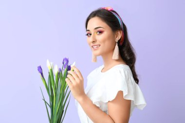 Yaratıcı makyajı ve mor arka planda süsen çiçekleri olan genç bir kadın. Uluslararası Kadınlar Günü