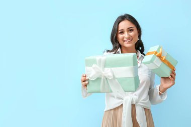 Yaratıcı makyajlı genç bir kadın mavi arka planda hediye kutuları tutuyor. Uluslararası Kadınlar Günü