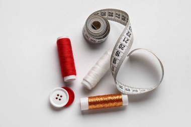 Ölçüm bandı ve beyaz arkaplanda düğmeleri olan iplik makaraları