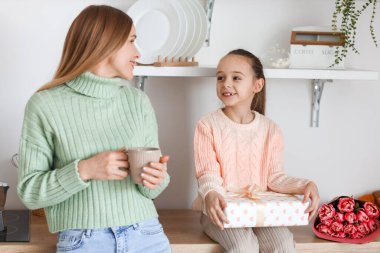 Bir fincan çayla mutlu anne, küçük kızı ve Uluslararası Kadınlar Günü 'nde mutfakta hediye.