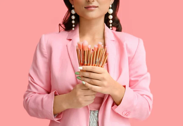 ピンクの背景にブラシのセットを持っている女性 クローズアップ 国際女性デー — ストック写真