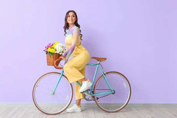 Женщина Велосипеде Корзиной Полной Цветов Фиолетовом Фоне Международный Женский День — стоковое фото
