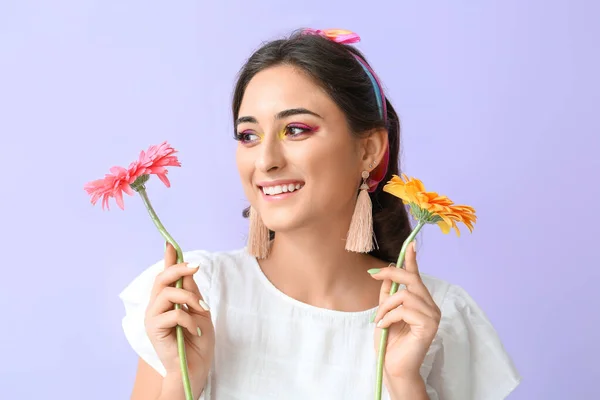創造的なメイクと紫色の背景を脇に見てガーベラの花を持つ若い笑顔の女性 国際女性デー — ストック写真
