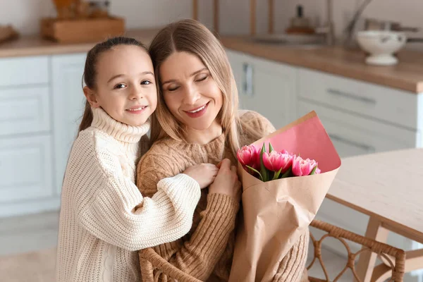 国际妇女节那天 快乐的妈妈带着一束郁金香和她的小女儿在厨房里 — 图库照片