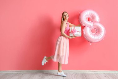 Hediye kutuları ve pembe duvarın yanında şekil 8 şeklinde balonu olan güzel bir kadın. Uluslararası Kadınlar Günü kutlamaları