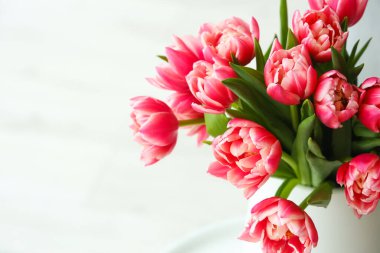 Oturma odasındaki küçük masanın üzerinde lale çiçekleri olan vazo, yakın plan.