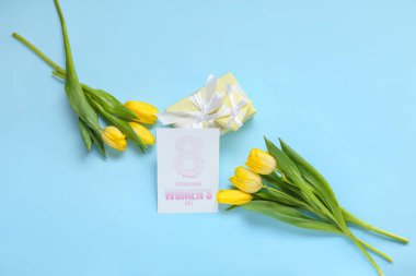 8 Mart Uluslararası Kadınlar Günü yazılı tebrik kartı, mavi arka planda hediye kutuları ve laleler