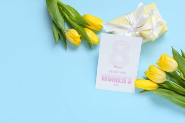 8 Mart Uluslararası Kadınlar Günü yazılı tebrik kartı, mavi arka planda hediye kutuları ve laleler