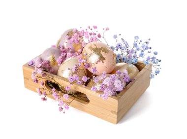 Güzel Paskalya yumurtaları ve beyaz arka planda çingene çiçekleri olan ahşap kutu.