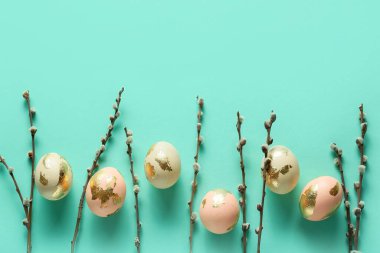 Composition with beautiful Easter eggs and pussy willow branches on color background