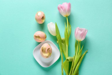 Renkli arkaplanda güzel Paskalya yumurtaları ve lale çiçekleri olan kompozisyon