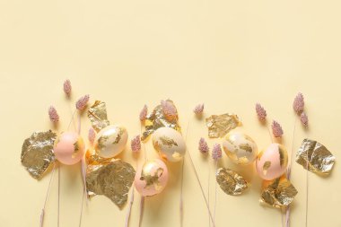 Renkli arkaplanda güzel Paskalya yumurtaları, folyo ve kurumuş çiçekleri olan kompozisyon