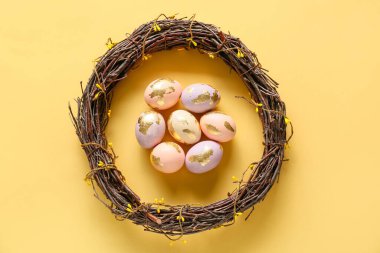 Renkli arkaplanda güzel Paskalya yumurtaları ve çelengi olan kompozisyon