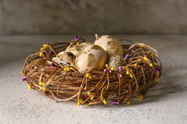 Açık arkaplanda Paskalya yumurtaları olan hasır bir yuva.