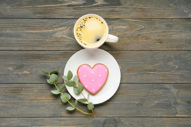 Bir fincan kahve, lezzetli kurabiyeler ve ahşap zemin üzerinde okaliptüs dalları olan kompozisyon. Uluslararası Kadınlar Günü kutlamaları