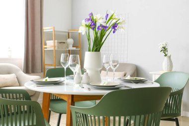 Uluslararası Kadınlar Günü kutlamaları için ışık odasında servis edilen süsen çiçekli vazo ve masa.