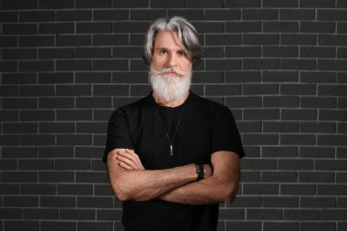 Siyah arka planda yakışıklı, olgun, sakallı bir adamın portresi.