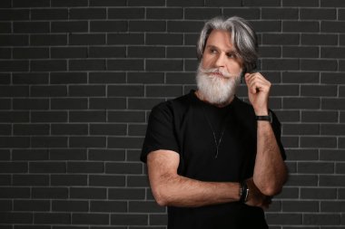 Siyah arka planda yakışıklı, olgun, sakallı bir adamın portresi.