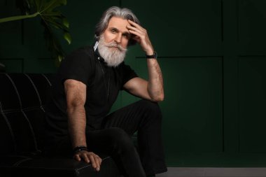 Karanlık odadaki yakışıklı, olgun sakallı adamın portresi.