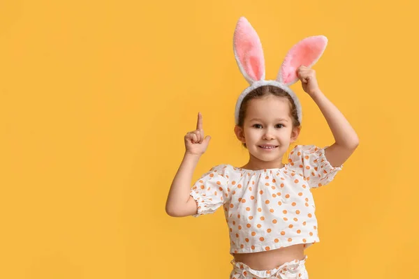 Grappig Klein Meisje Met Konijnenoren Wijzend Naar Iets Gele Achtergrond — Stockfoto