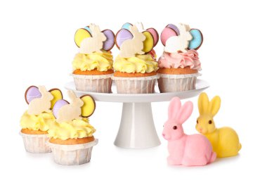 Beyaz arka planda lezzetli paskalya çörekleri ve tavşanlarla durun.