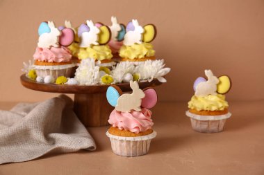 Lezzetli paskalya çörekleri, çiçekler ve kahverengi arka planda yumurtalar