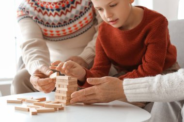 Büyük annesi ve büyük babasıyla evde Jenga oynayan küçük bir çocuk.