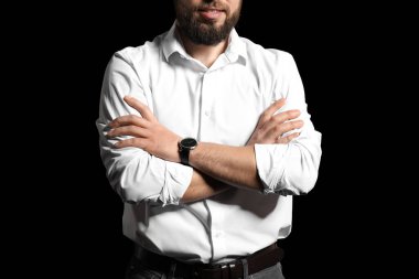 Koyu arkaplanda çapraz kollu şık bir adam.