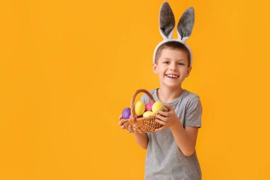 Tavşan kulaklı komik küçük çocuk ve sarı arka planda Paskalya sepeti.
