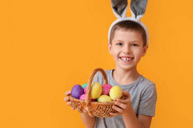 Tavşan kulaklı komik küçük çocuk ve sarı arka planda Paskalya sepeti.