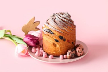 Lezzetli Paskalya pastası, lale çiçekleri, şekerler ve pembe arka planda yumurtalar.