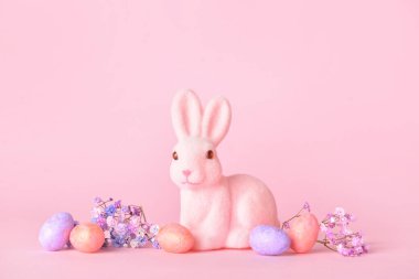 Tatlı Paskalya tavşanı, pembe arka planda yumurtalar ve çiçekler.