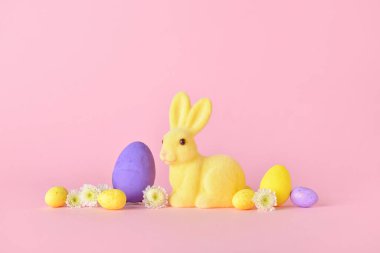 Tatlı Paskalya tavşanı, pembe arka planda yumurtalar ve çiçekler.