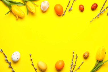 Güzel Paskalya yumurtaları, söğüt dalları ve sarı arka planda lale çiçekleri.