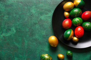 Yeşil arka planda zarif Paskalya yumurtaları olan tabak.